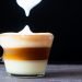 Café cubano com leite, tirado da camada espumosa, com fundo preto.