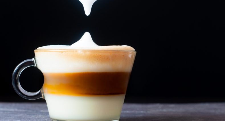 Café cubano com leite, tirado da camada espumosa, com fundo preto.
