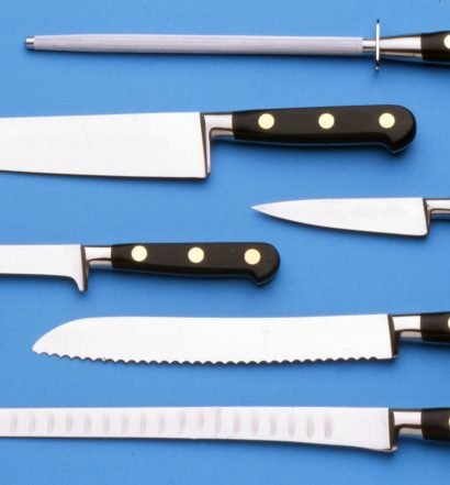 Conjunto de facas de cozinha e chaira sobre fundo azul mostrando diferentes tipos de lâminas