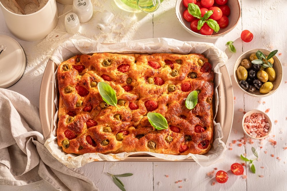 Focaccia italiana com tomates cereja, azeitonas e manjericão fresco, para o Dia Mundial do Pão