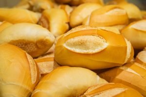 Pães franceses frescos e dourados empilhados em padaria artesanal no Dia Mundial do Pão