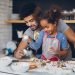Pai e filha sorrindo, preparando receitas com ovos e farinha na cozinha, aprendendo a cozinhar juntos e se divertindo.