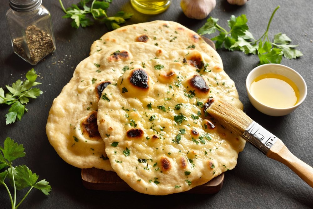 Pão Naan indiano fresco com ervas e azeite, perfeito para acompanhar pratos no Dia Mundial do Pão