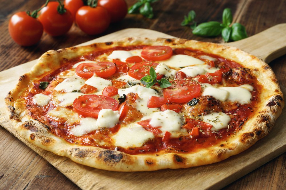 Pizza artesanal com queijo de búfala derretido, tomate e manjericão