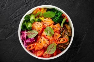 Tigela saudável com salmão, legumes variados e folhas verdes — alimentação equilibrada