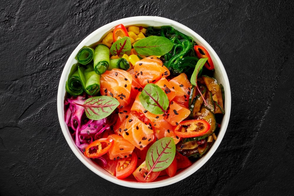 Tigela saudável com salmão, legumes variados e folhas verdes — alimentação equilibrada