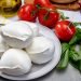 Porções de queijo de búfala sobre tábua de madeira com tomates-cereja e manjericão