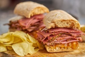 Sanduíches de pastrami clássicos com muitas fatias e batatas chips, perfeitos para um lanche saboroso
