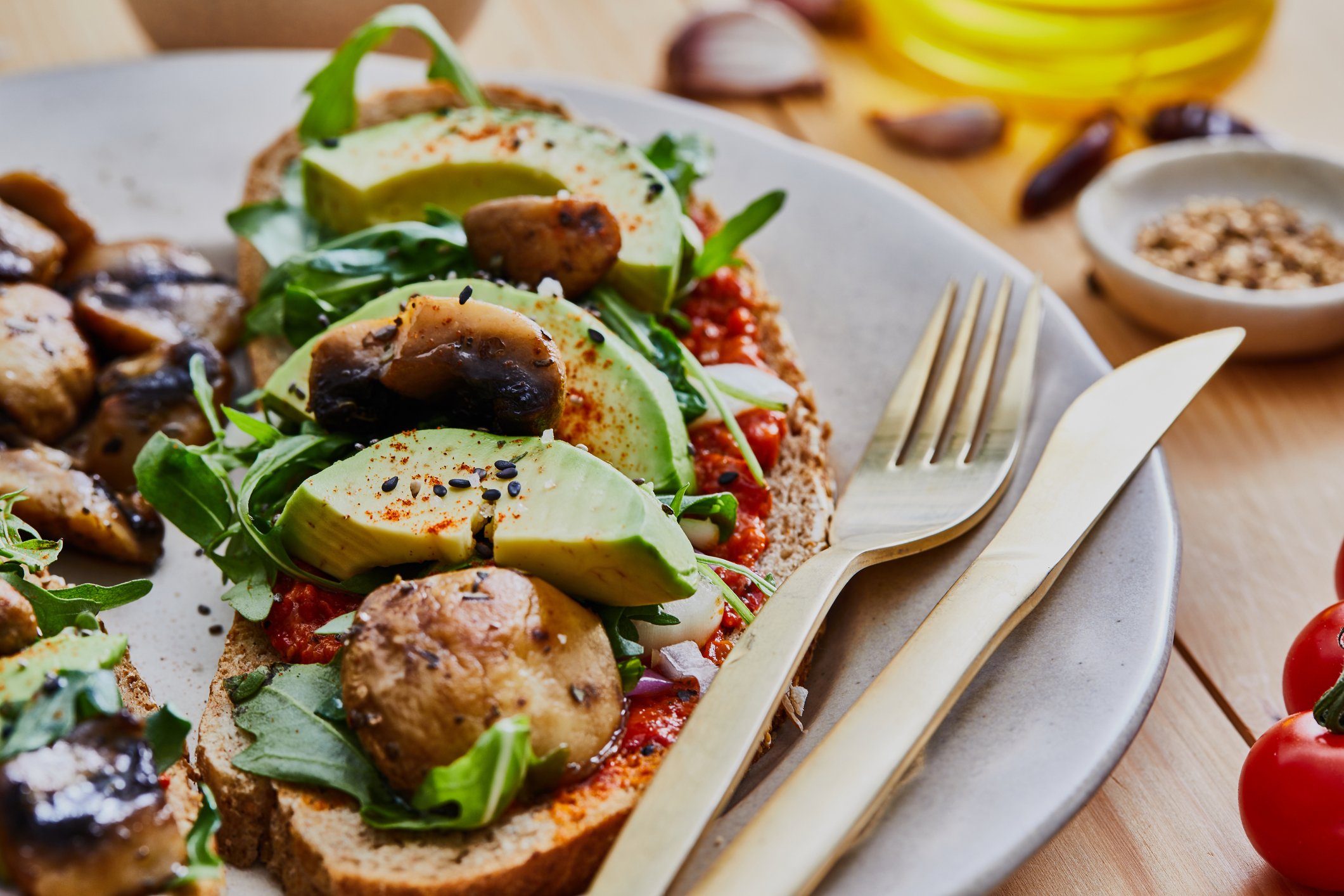 Torrada integral com abacate, cogumelos salteados, rúcula e creme de tomate — opção prática para o Dia Mundial do Veganismo.