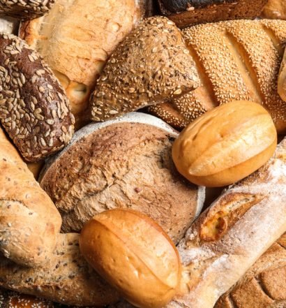 Variedade de pães artesanais frescos incluindo pão integral, baguete, pão de centeio e pão com sementes para celebrar o Dia Mundial do Pão