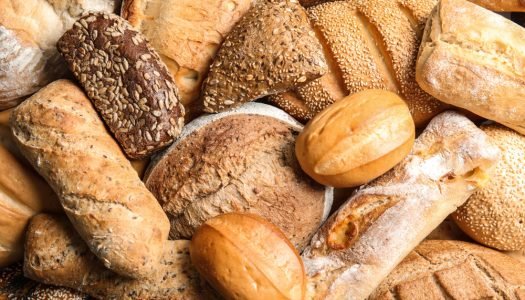 Variedade de pães artesanais frescos incluindo pão integral, baguete, pão de centeio e pão com sementes para celebrar o Dia Mundial do Pão