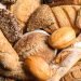 Variedade de pães artesanais frescos incluindo pão integral, baguete, pão de centeio e pão com sementes para celebrar o Dia Mundial do Pão