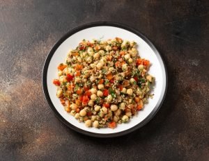 Prato com grão-de-bico cozido misturado com vegetais coloridos, leguminosa que ajuda a controlar triglicerídeos