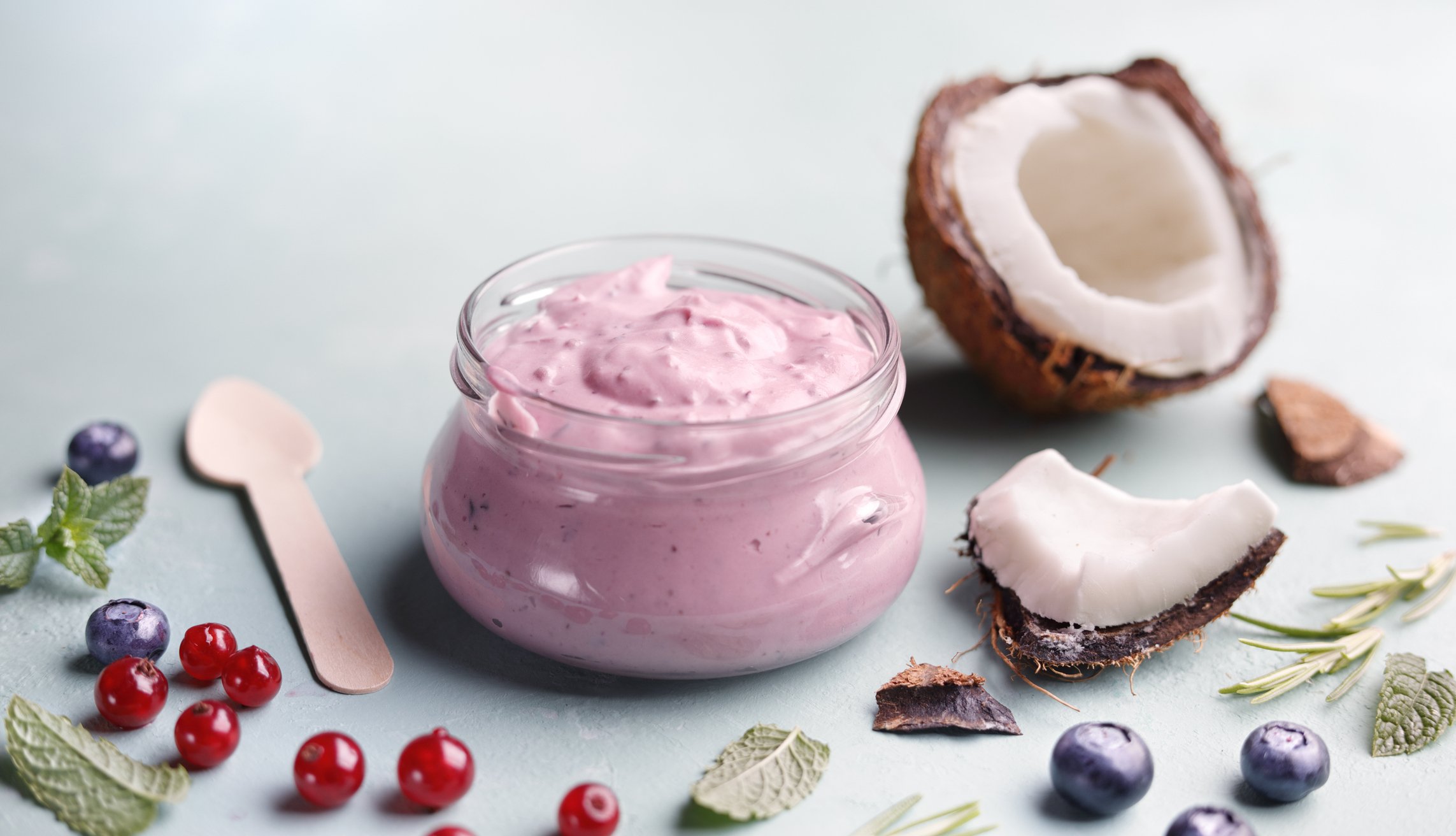 Iogurte rosa de frutas vermelhas com coco ralado em pote de vidro, acompanhado de coco fresco, amoras e framboesas - iogurte vegetariano