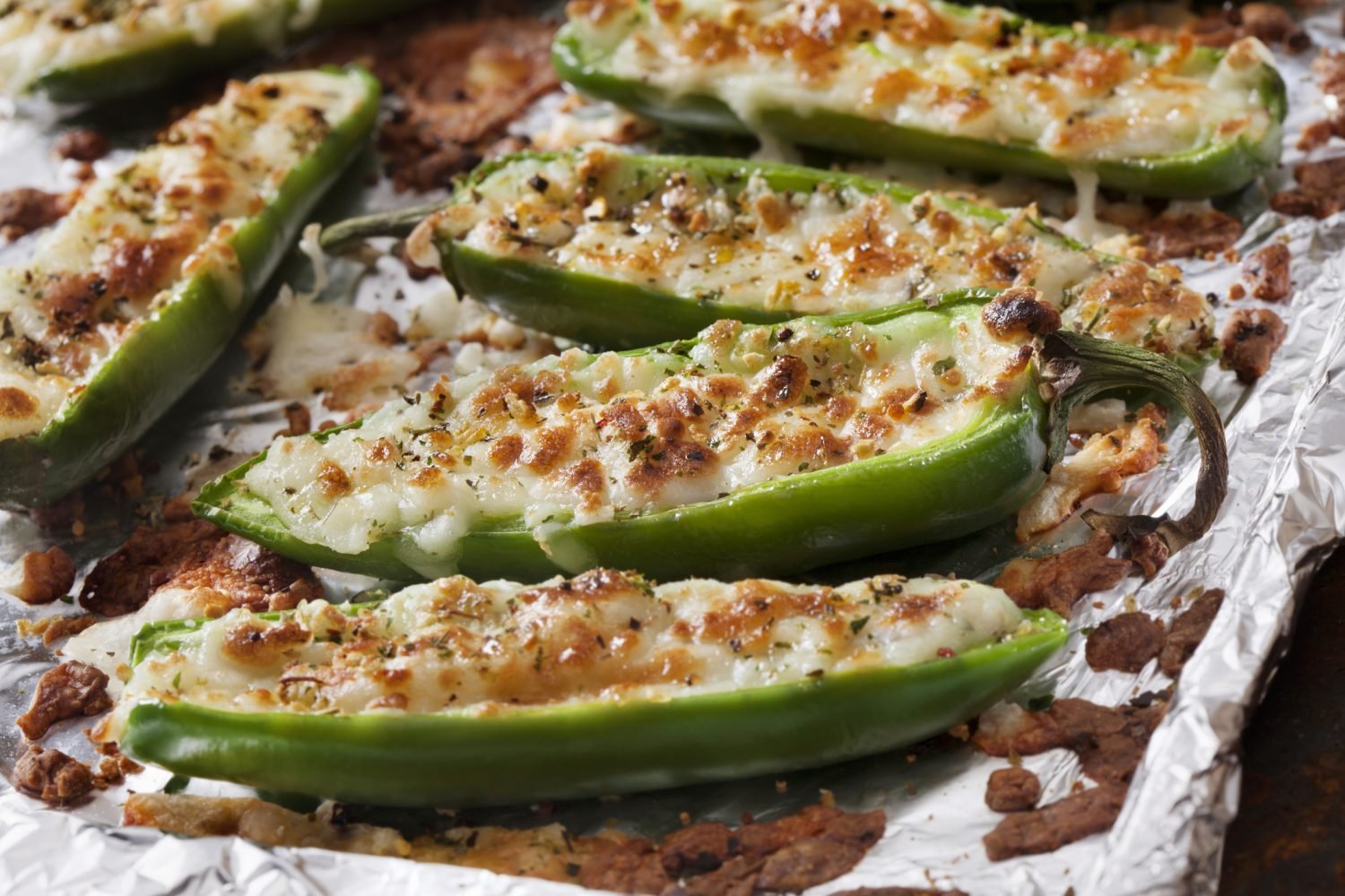 Pimentões verdes recheados com carne moída e queijo derretido assados em papel alumínio
