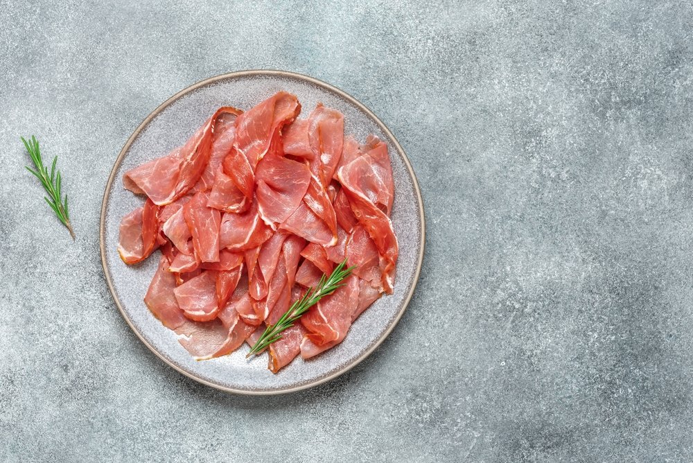 Prato cinza com fatias de Jamón Serrano e raminho de alecrim, representando o presunto cru espanhol.