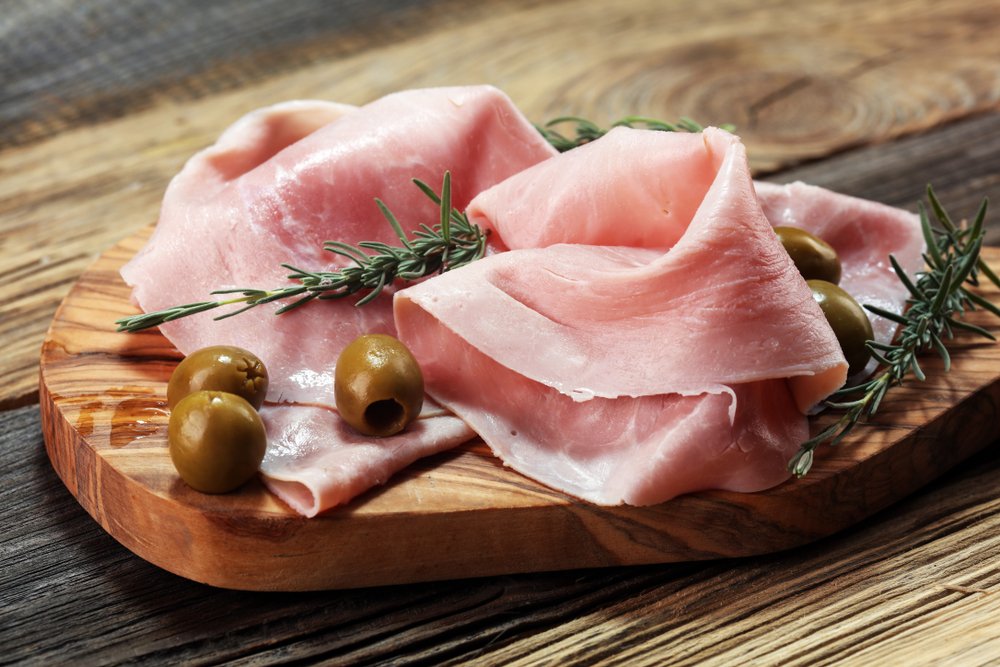 Presunto defumado fatiado em tábua rústica com azeitonas verdes e ramos de alecrim.