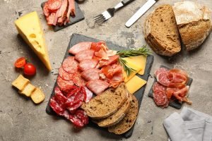 Tábua gourmet com diversos tipos de presunto, salame, queijo e pão; inspire-se para montar tábuas de frios.