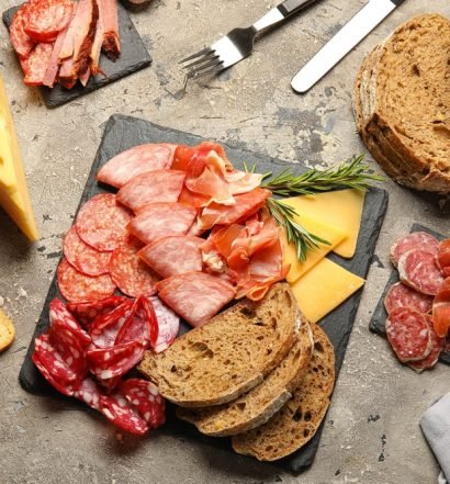 Tábua gourmet com diversos tipos de presunto, salame, queijo e pão; inspire-se para montar tábuas de frios.