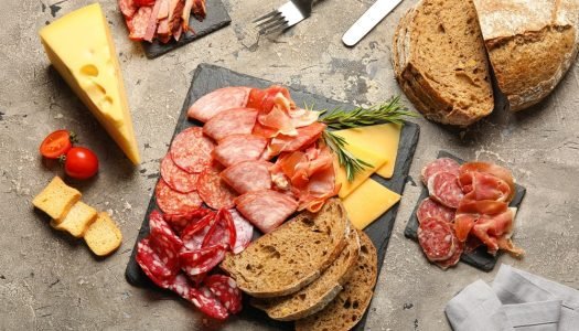 Tábua gourmet com diversos tipos de presunto, salame, queijo e pão; inspire-se para montar tábuas de frios.
