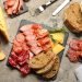 Tábua gourmet com diversos tipos de presunto, salame, queijo e pão; inspire-se para montar tábuas de frios.