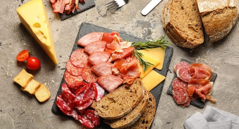 Tábua gourmet com diversos tipos de presunto, salame, queijo e pão; inspire-se para montar tábuas de frios.