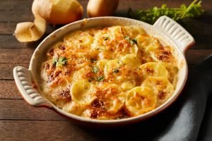 Acompanhamento de ceia de Natal simples, batata gratinada cremosa e dourada em travessa de cerâmica