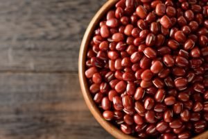 Feijão-azuki em close, grão vermelho em tigela sobre mesa de madeira – tipo de feijão entre os 11 grãos mais consumidos