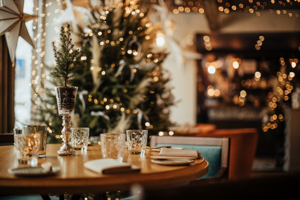 Mesa de ceia de Natal simples com decoração minimalista e elegante, taças transparentes e luzes douradas para impressionar os convidados