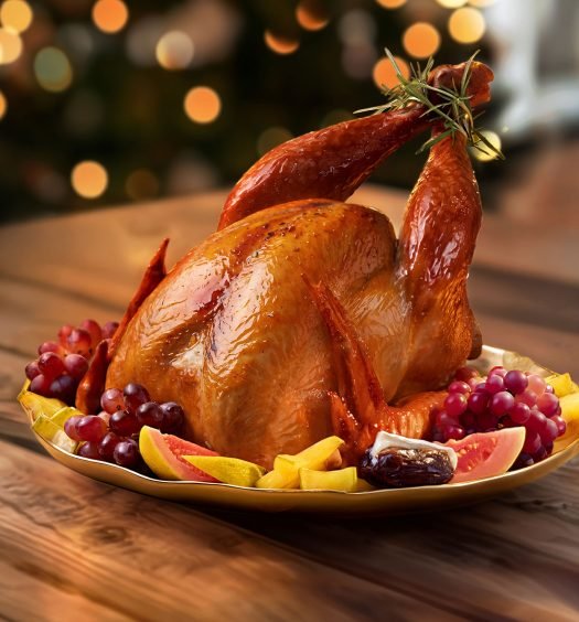 Peru assado dourado de Ceias no Pão para ceia de Natal e Ano Novo em mesa de madeira, com decoração natalina desfocada ao fundo