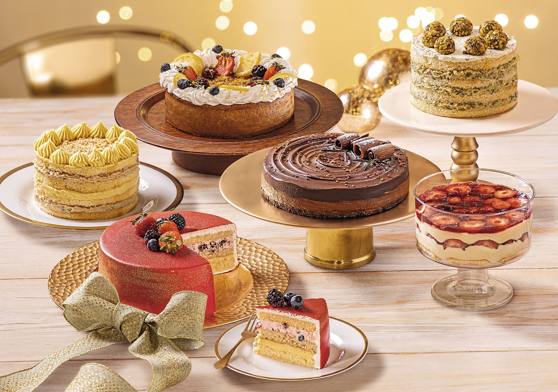 Sobremesas de fim de ano da Ceias no Pão com variedade de bolos e tortas decoradas em mesa natalina iluminada