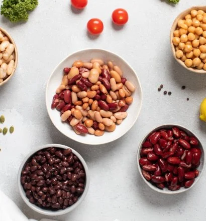 Vários tipos de feijão em tigelas sobre a mesa, como feijão-carioca, feijão-preto, feijão-branco e grão-de-bico, ilustrando os 11 grãos mais consumidos