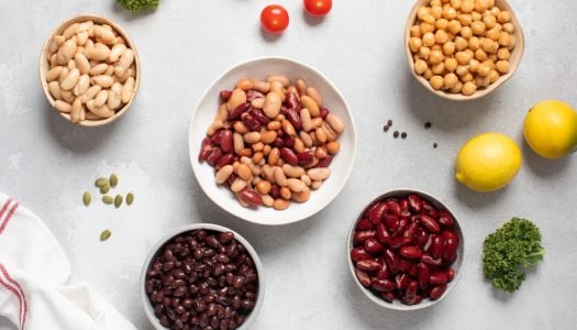 Vários tipos de feijão em tigelas sobre a mesa, como feijão-carioca, feijão-preto, feijão-branco e grão-de-bico, ilustrando os 11 grãos mais consumidos