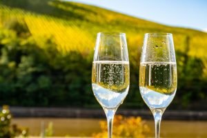 Duas taças de espumante tipo flute em primeiro plano, perfeitas para demonstrar como segurar a taça de espumante na degustação.